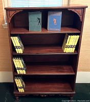 Frontal view of wooden bookcase filled with Nancy Drew books arranged on shelves