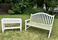 Front view of white wooden garden bench and matching planter on grass, showing overall condition and weathering.