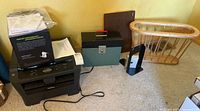 Brother laser printer on floor with manuals and cables next to file box and wooden basket, showing full lot contents.