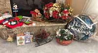 Overview of various Christmas decorations including floral wreaths, mini sleigh, stockings, holiday cards, and small figurines on granite ledge and floor.