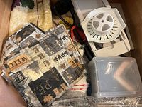 View of food slicer with detachable circular blade guard, handle, and kitchen cloths with fall-themed prints inside drawer.