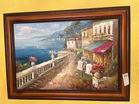 Full view of one framed oil painting depicting Mediterranean coastal terrace with sea view, shrubbery, and flowers in rich colors. Wooden frame with warm tone and decorative top edge.
