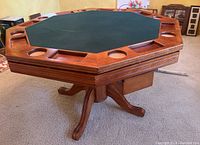 View of octagonal wooden games table with finished green felt top and multiple cup holders and card/tray compartments around the edges.