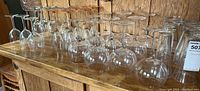 Multiple clear stemmed wine glasses of various sizes arranged on a wooden surface.