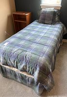 Twin bed with plaid bedding, showing full bed and mattress.