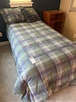 Twin bed made with padded bedding and pillows, image shows bed from upper corner