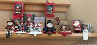 Full view of vintage Christmas stocking holders displayed on wooden shelf, some in original boxes showing characters like snowmen, Santa Claus, and reindeer.