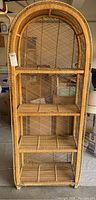 Front view of vintage wicker arched shelf with four shelves and lattice back.
