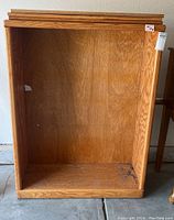 Front view of wooden bookcase showing interior and adjustment slots for shelves. Bottom inside surface has black marks.