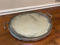 Side angle of round vanity tray showing distressed mirror surface and metal rim with handles