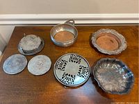 Overview of entire collection showing various silver plate trivets, baskets, coasters.