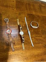 Four women's wristwatches laid out on wooden surface showing overall designs and condition.