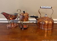Full view of all three copper items: teapot, gravy boat with warming stand, and butter warmer dish
