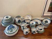 Full tableware and serveware collection displayed in stacks on a wooden surface