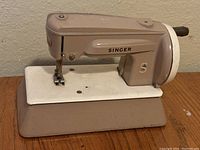 Full view of the vintage Singer Sew Ready toy sewing machine showing beige colored body and white base with Singer branding.