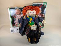 Three Cabbage Patch Kids dolls including unboxed 1989 Billy Bashful Happy Hobo clown doll with colorful clothes in front, two boxed dolls in holiday-themed outfits behind.