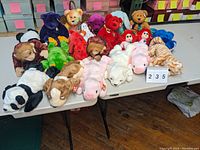 Photo showing a large assortment of 17 Ty Beanie Babies stuffed animals arranged on a table in various colors and animal types.