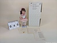 Full shot of the Danielle Little Ballerina doll standing next to its original box and accompanying paperwork.