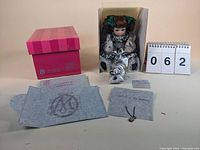 Photo showing the Marie Osmond doll seated in original packaging with pink box, certificate, and packaging tissues around it.