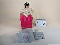 Full lot showing Princess Rosebud doll seated on her original pink box with lot number display and certificate/necklace accessories arranged below.