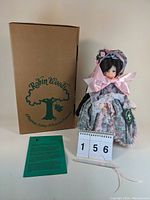 Front view photo of the Elizabeth Jane doll standing next to the original box and certificate, highlighting the doll's dress and bonnet.