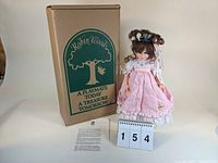 Full view of the Lisa Marie doll standing next to the original Robin Woods branded box, with certificate and letter displayed.