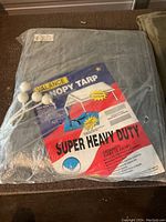 Packaged gray Valance decal canopy tarp showing label with product features including super heavy duty, grommets every 18 inches, and outdoor use.