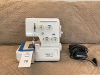 Front view of Janome My Lock 134D sewing machine with foot pedal next to it.