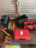 Overview of tools including saws, hammer, tool bags, and paint can on a table.