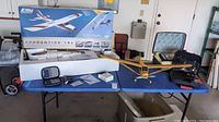 Photo showing Apprentice 15e Elite airplane box next to King Hx-239 yellow airplane with radio equipment and accessories on table.