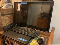 Sony 26 inch All In One desktop computer, black flat screen, with black Dell laptop, keyboard, mouse, and mousepad visible, with cables