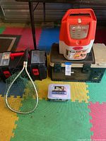 Overall view of all tackle items including tackle boxes, live bait bucket, cast net box, and fishing net laid on colored foam mat.