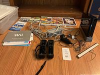 Full lot photo showing Nintendo Wii console, two controllers, nunchuk, sensor bar, cables, manuals, and five game cases.