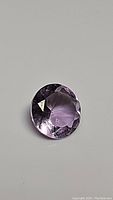 Close-up image of round faceted natural purple Brazilian amethyst gemstone showing clarity and cut.