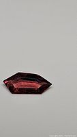 Bright red elongated fancy cut spinel gemstone on white background
