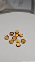 Top view of 10 round golden citrine cabochon gemstones on a white background.