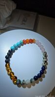 Round stretchy bracelet made of mixed natural gemstone beads in various colors and patterns displayed on a white surface.