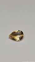 Close-up photo of 1.78 carat natural golden citrine pear cut gemstone against a plain background.