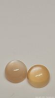 Two round peach moonstone cabochons side by side, showcasing color and surface polish.