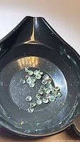 Loose round alexandrite gemstones approx 2mm diameter under daylight showing greenish tint.