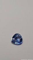 Close-up photo of the pear cut natural blue sapphire gemstone showing its light cornflower color and facets.