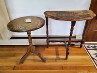 Photo showing round pedestal table and demilune side table side by side on hardwood floor against wall