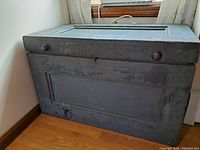 Front view of antique painted wood tool chest showing paneled front with two round knobs and keyhole.