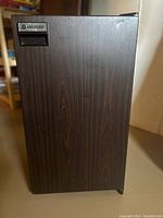 Closed view of the Absocold bar fridge showing the woodgrain front door and brand logo.