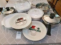 Overview of the lot showing 3 metal pots with lids and 2 ceramic pie plates with printed recipes for strawberry and apple pie.