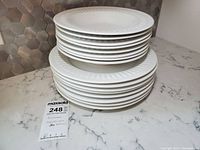Stack of 8 dinner plates and 8 salad/stew bowls in white porcelain with embossed rim detail.