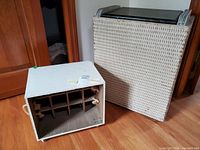 Photo showing the wicker hamper standing upright and the white painted beverage crate lying on its side revealing internal partitions.