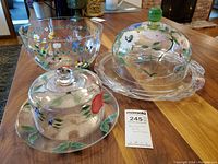 Set on wooden table showing entire salad bowl with floral hand painting, and the two domes with plates.
