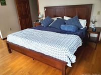 Full view of king-size hardwood platform bed frame with headboard, footboard and side rails assembled in bedroom