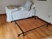 Full view of one twin bed frame assembled with bedding and pillows on top, including a textured blanket, pillows, and mattress.